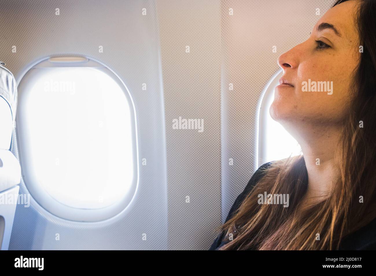 A young woman sitting in airplane seat by window Stock Photo