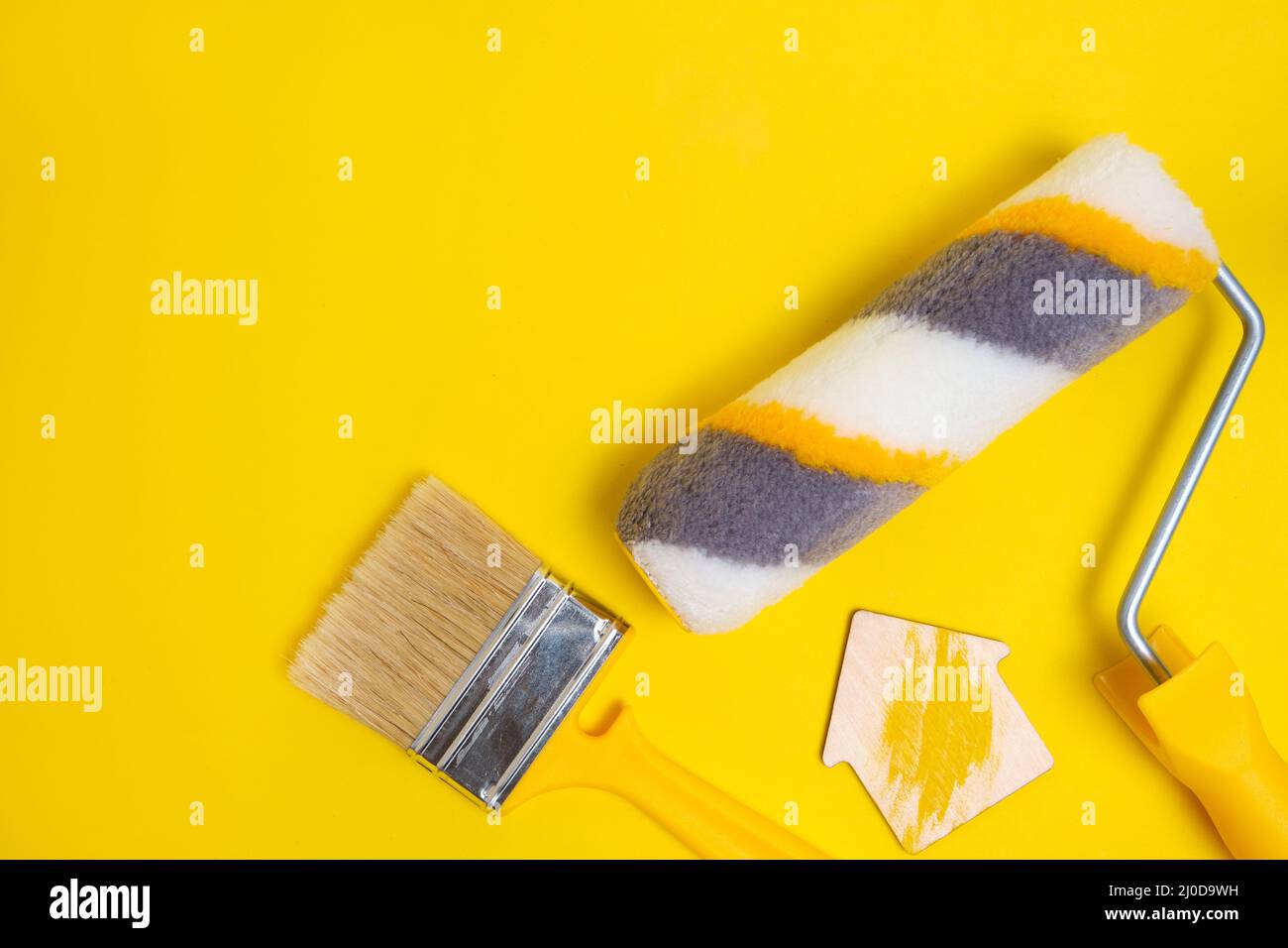 Paint roller, shield brush for painting walls on a yellow background