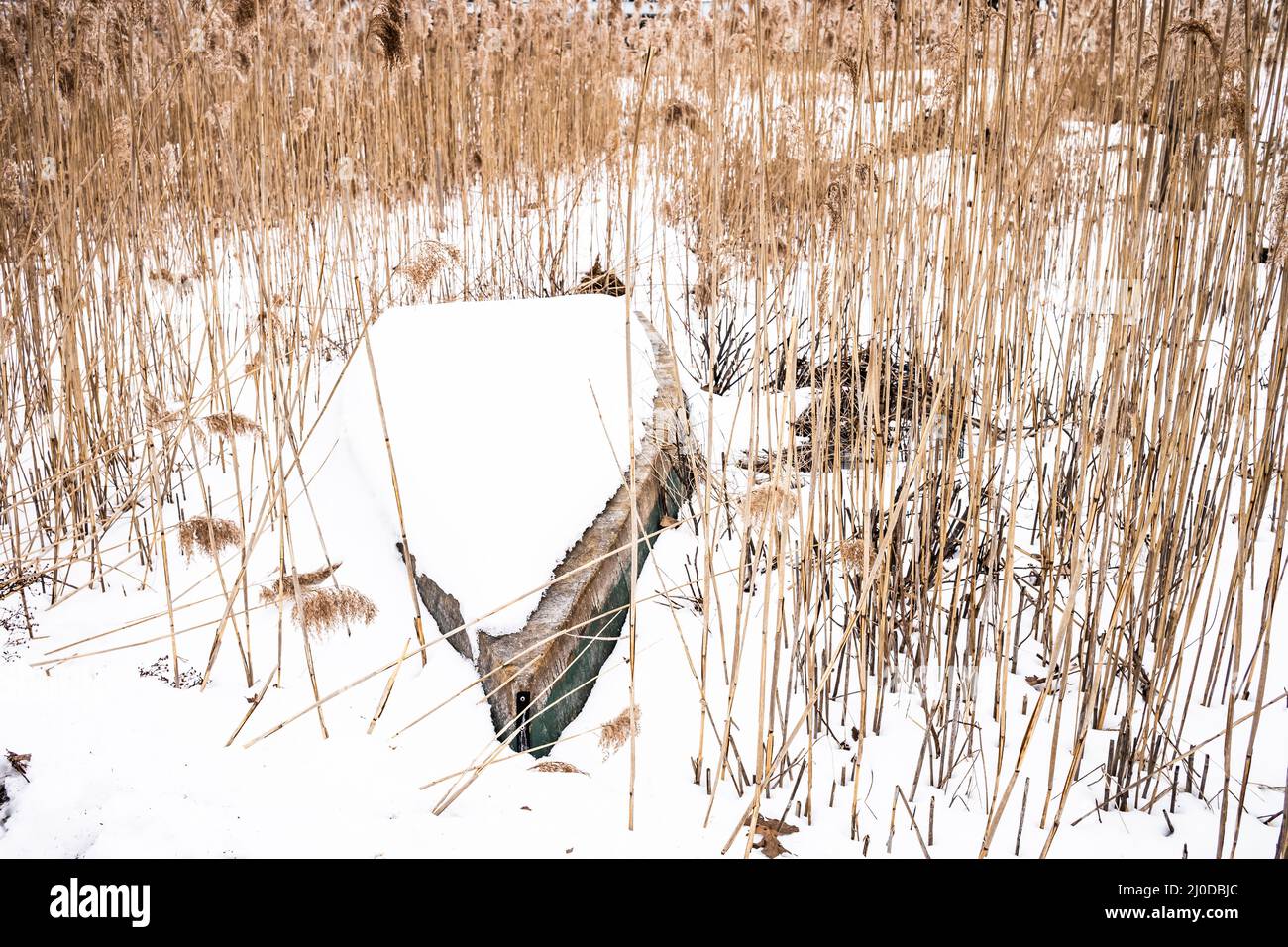 This Dingy was just left in a field on sea grass, and is now covered with snow until Spring when its owner will come looking for it once more. Stock Photo