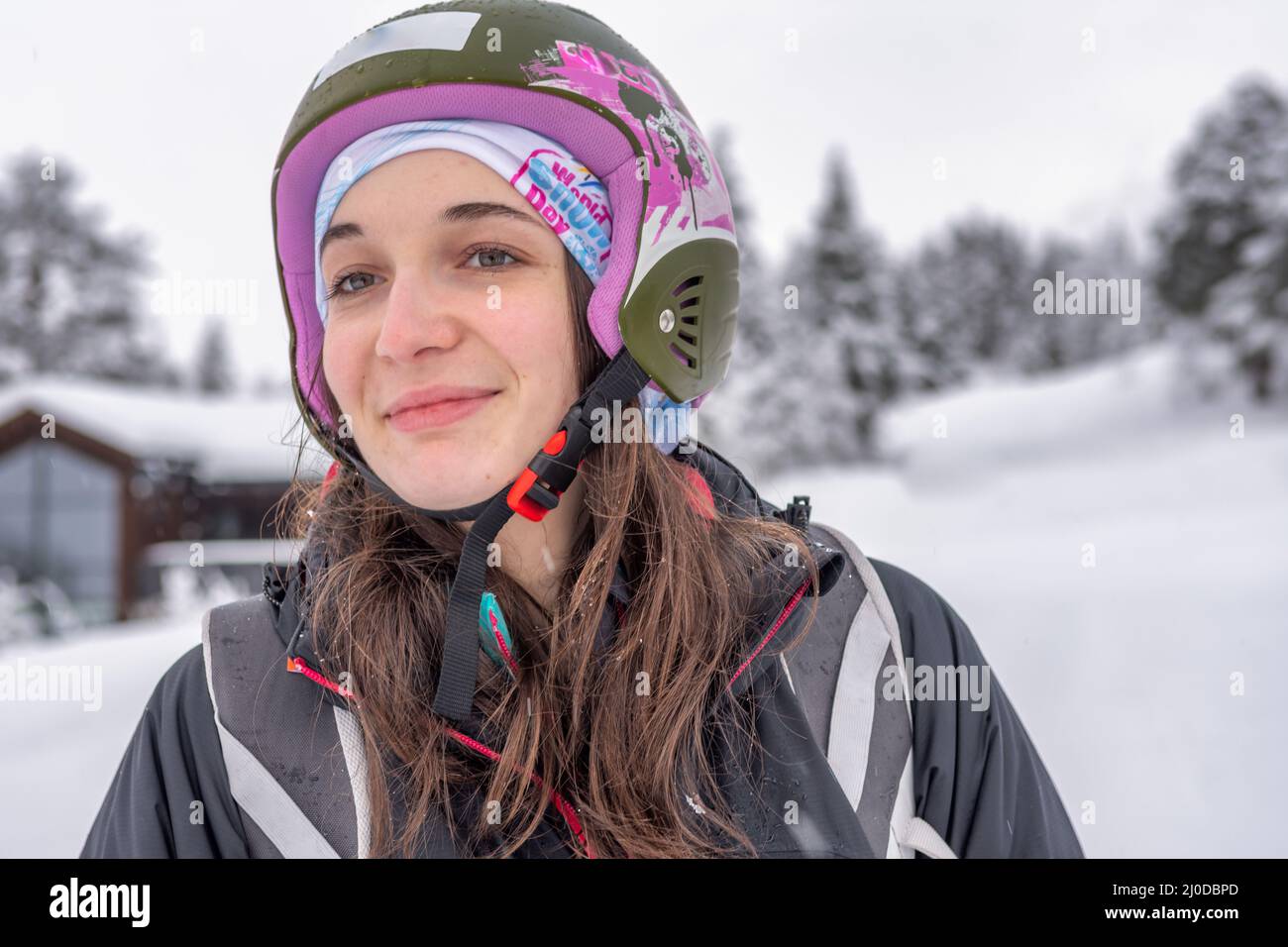 Women with brown hair smiling and looking, wearing ski wear and helmet