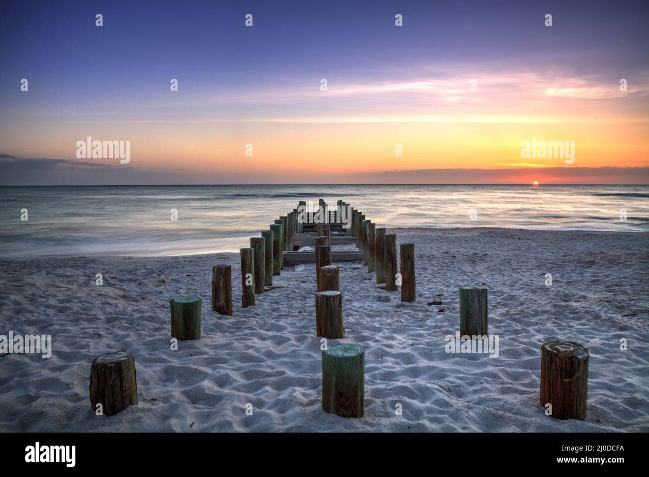 Ruins of the old Naples Pier at sunset on the ocean Stock Photo