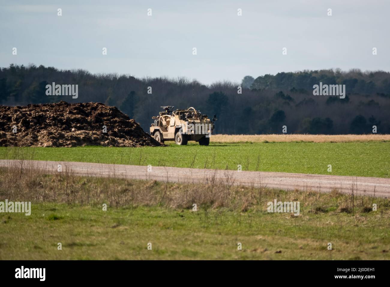 British army Supacat Jackal rapid assault, fire support and reconnaissance vehicle in action on a military training battle exercise, blue sky cloud Stock Photo