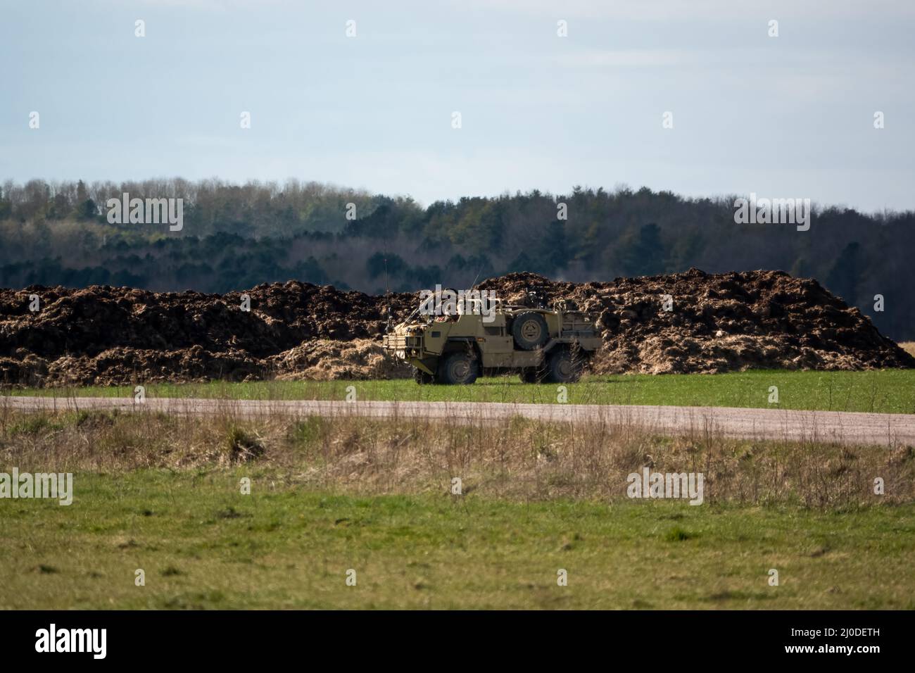 British army Supacat Jackal rapid assault, fire support and reconnaissance vehicle in action on a military training battle exercise, blue sky cloud Stock Photo