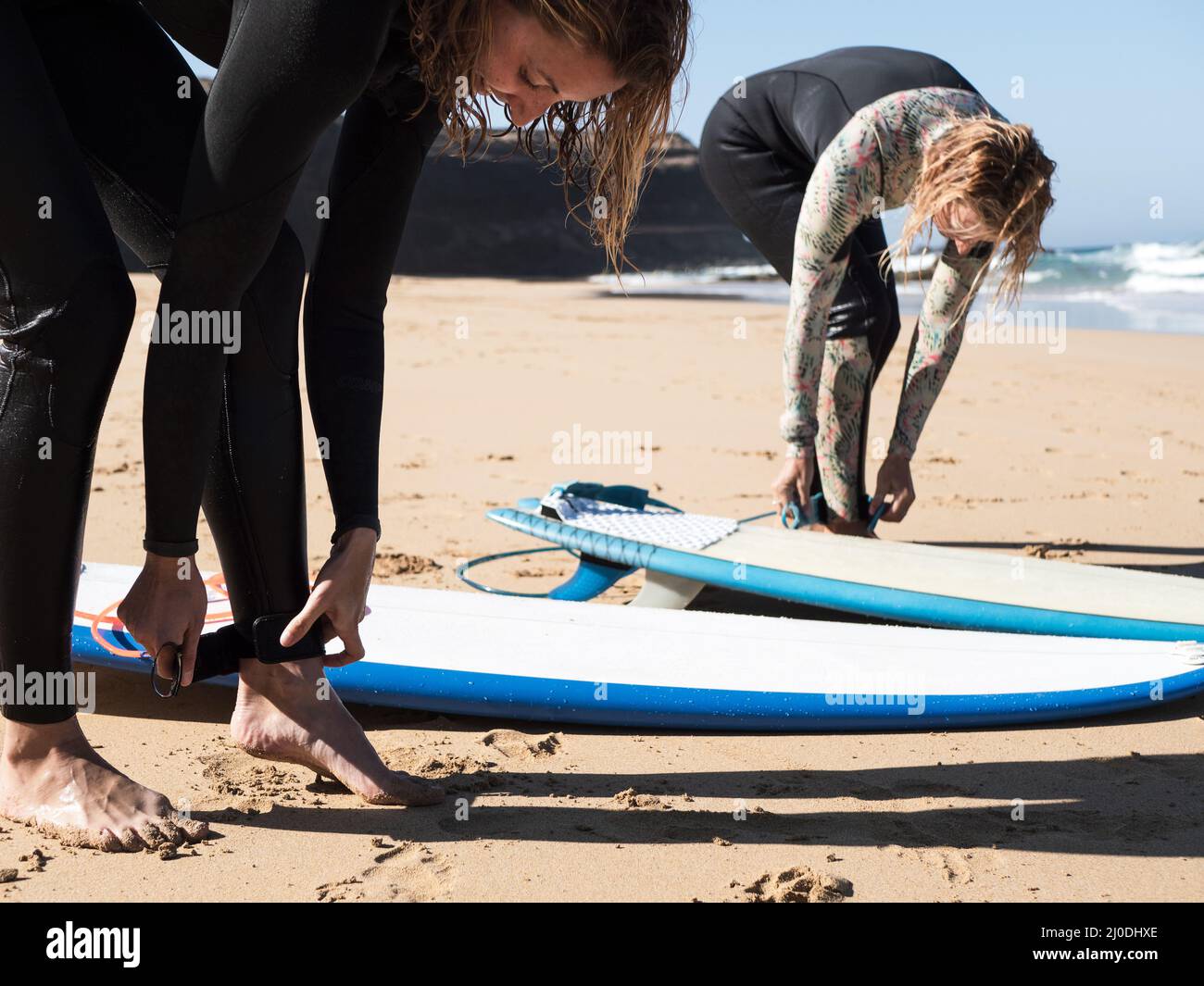 Surfer females attaching surf safety leash to their ankle Stock Photo
