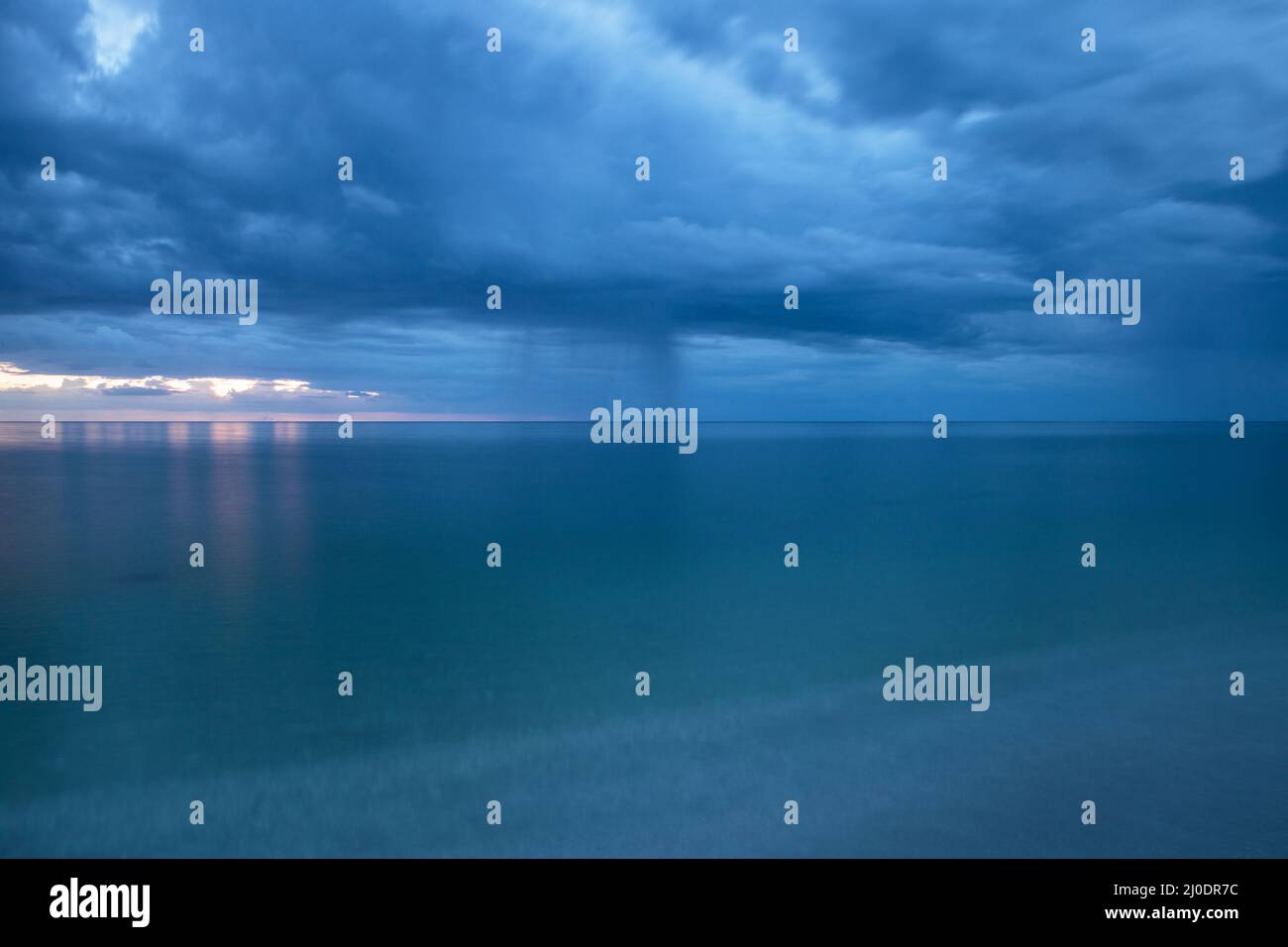 Rain pours from dark clouds over Clam Pass Beach in Naples, Florida Stock Photo