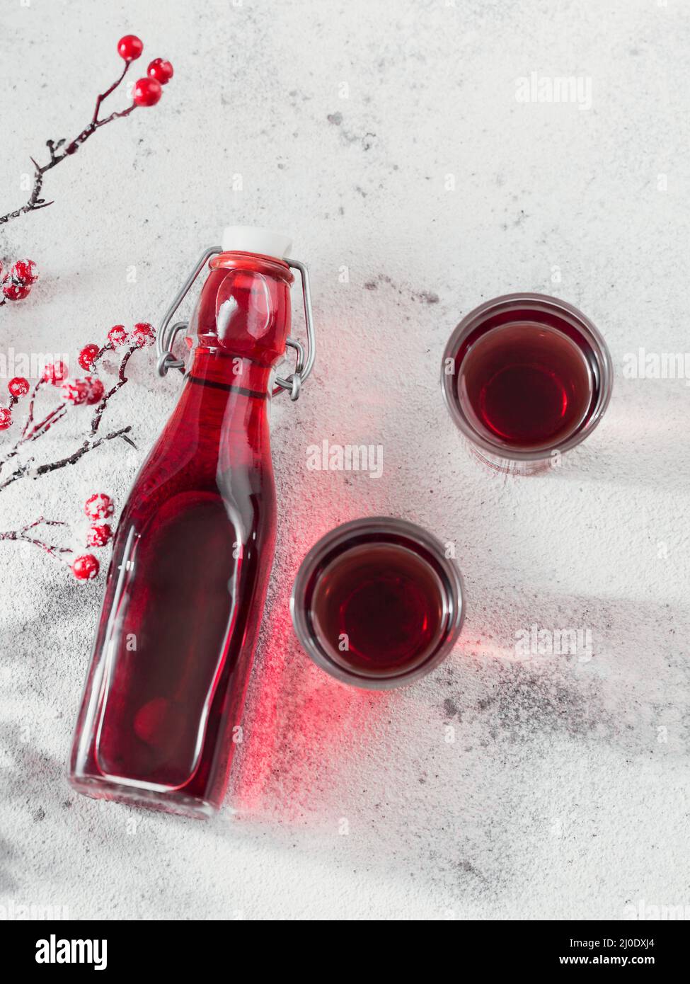 Homemade infused vodka, tincture or liqueur of red cherry on white background. Berry alcoholic drinks concept. Stock Photo