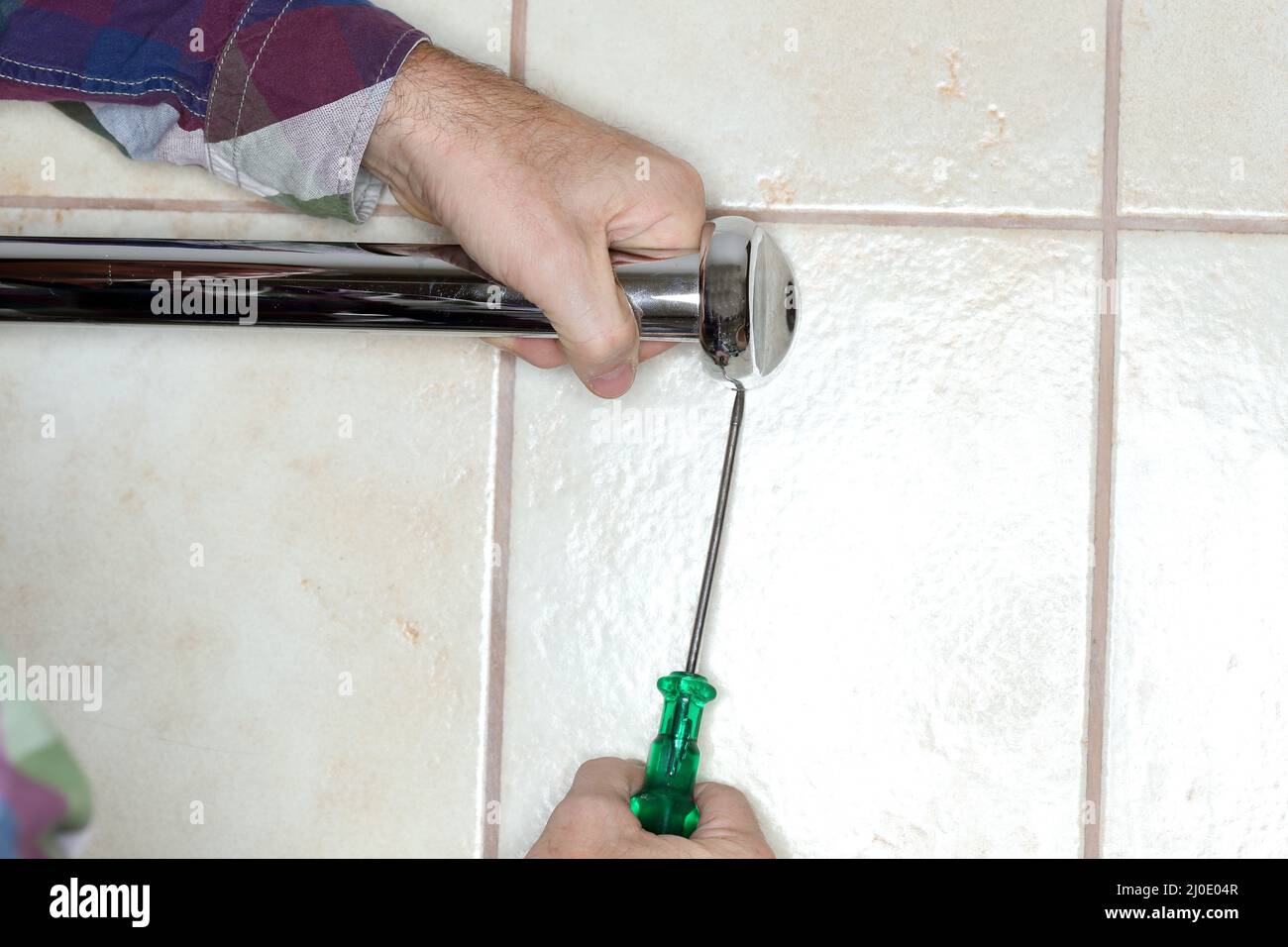 Worker is mounting a towel holder on a wall Stock Photo