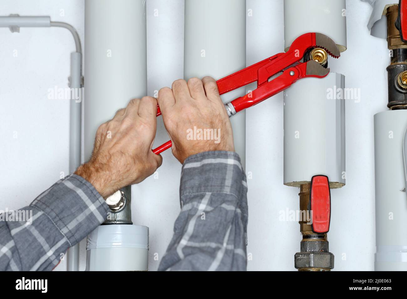 Worker with gripper in hand is fixing a pipe Stock Photo