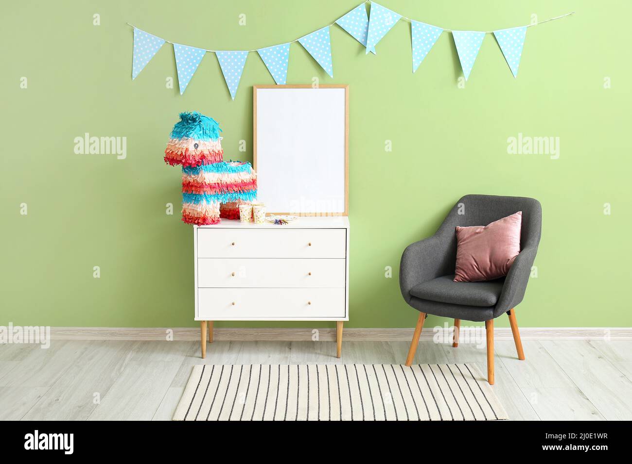 Mexican pinata with frame on chest of drawers and armchair near green ...