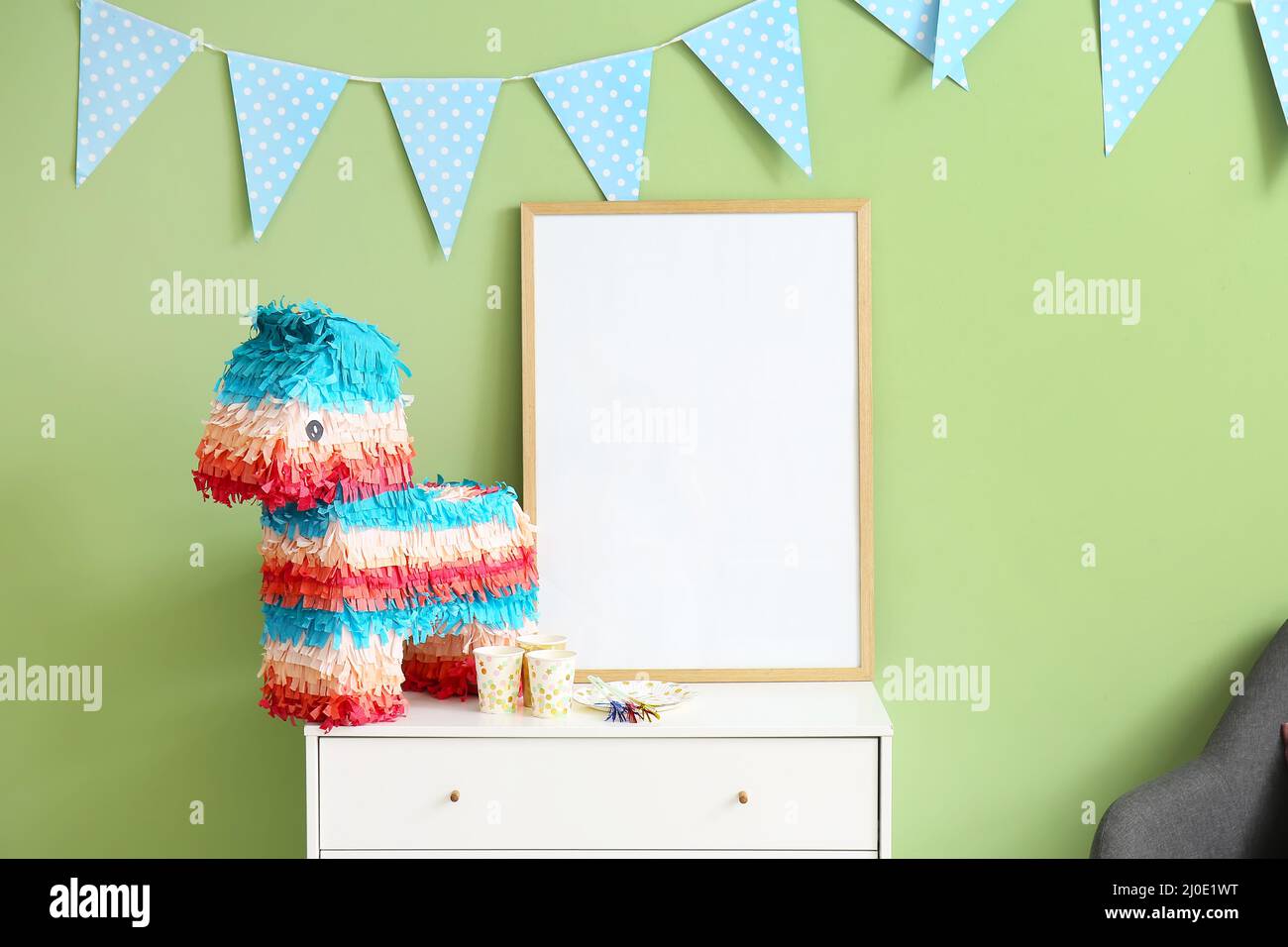 Mexican pinata in shape of horse and frame on shelf near green wall ...