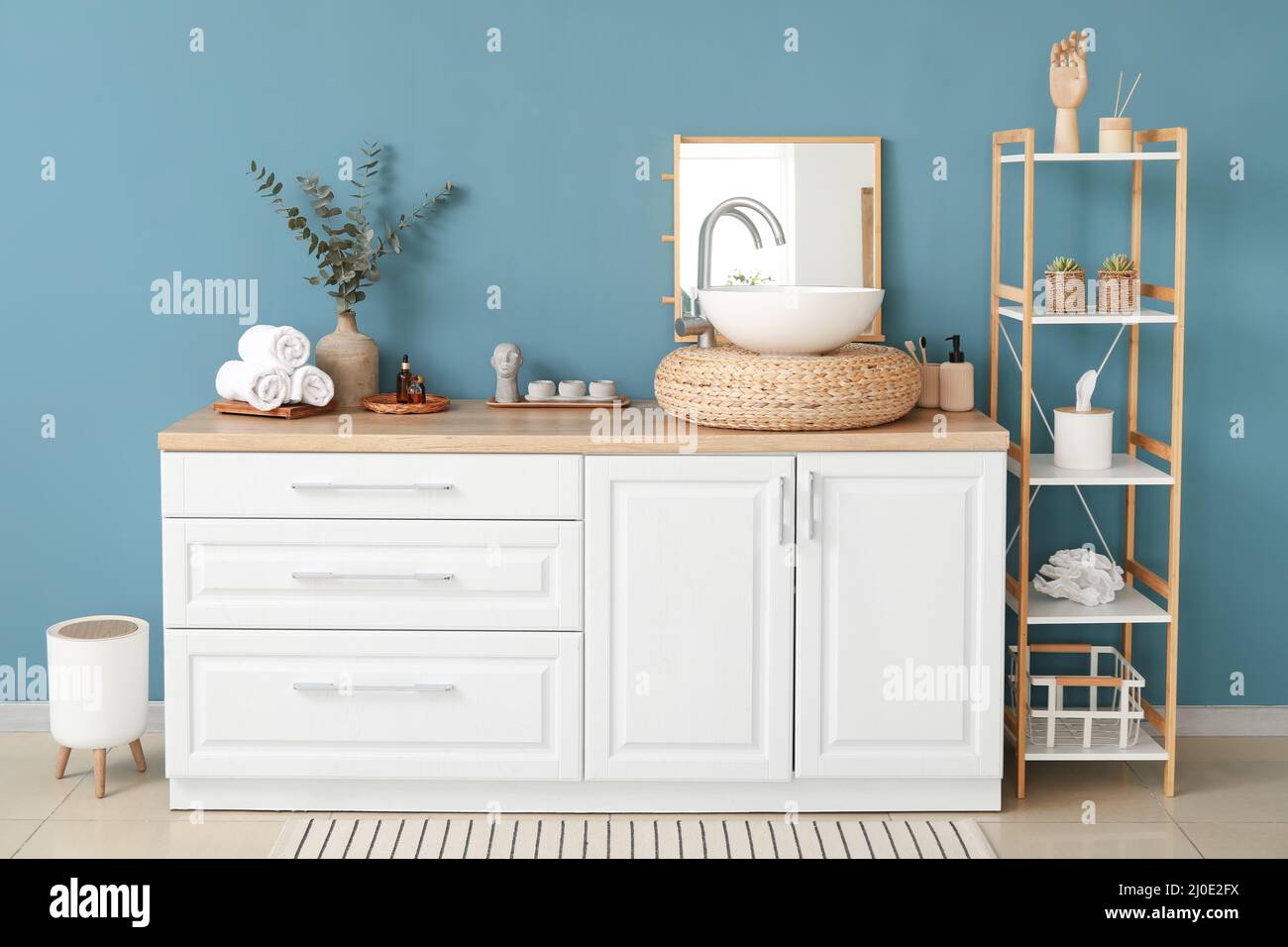 Interior of stylish bathroom with sink, shelving unit and blue wall