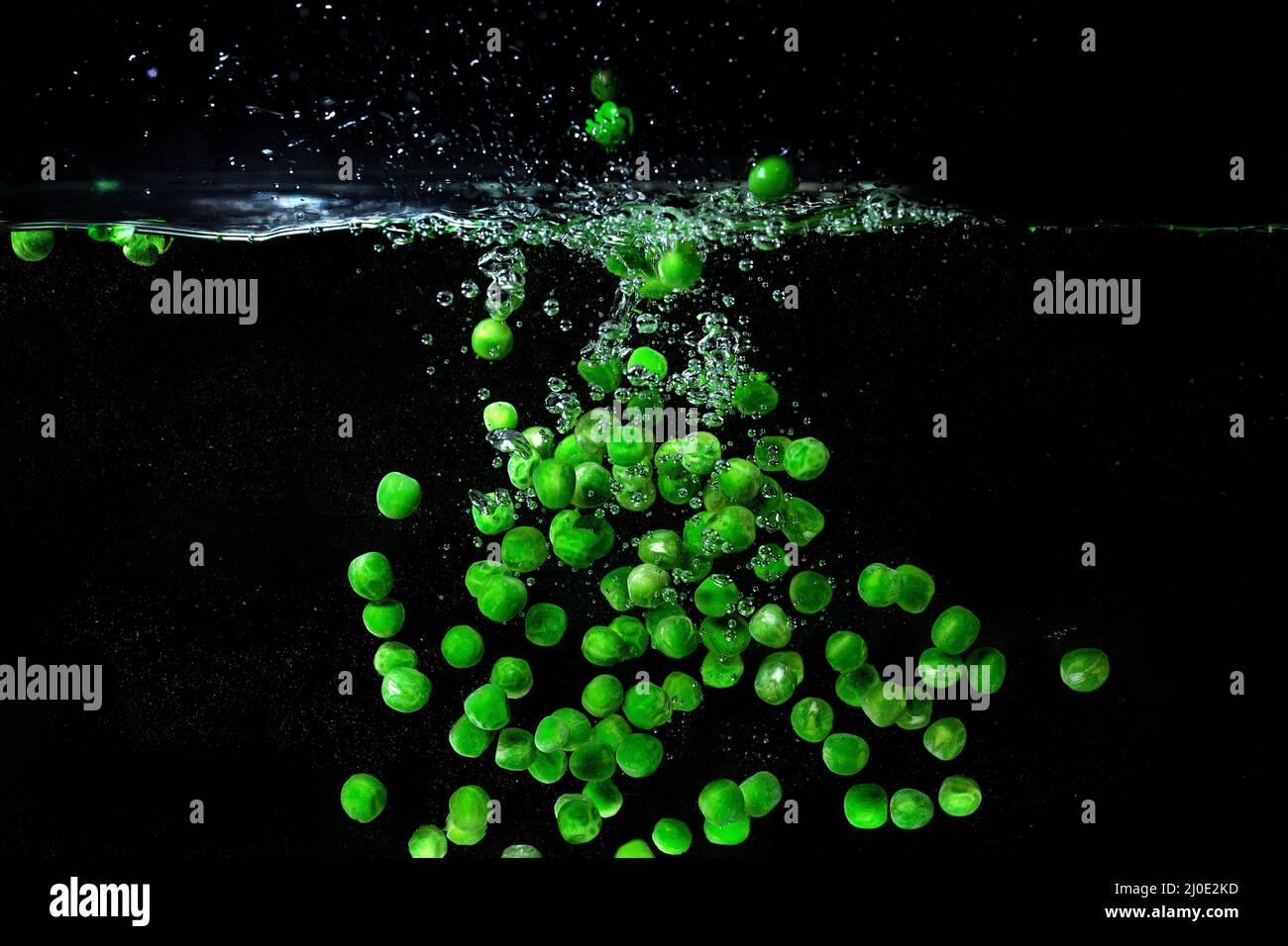 green peas falling in the boiling water on dark background. Underwater