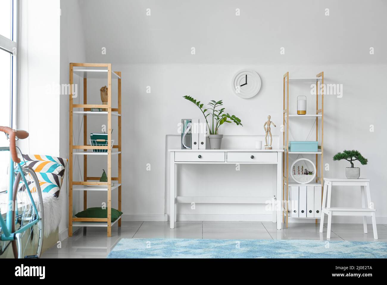 Interior of light living room with table, clock and shelving units