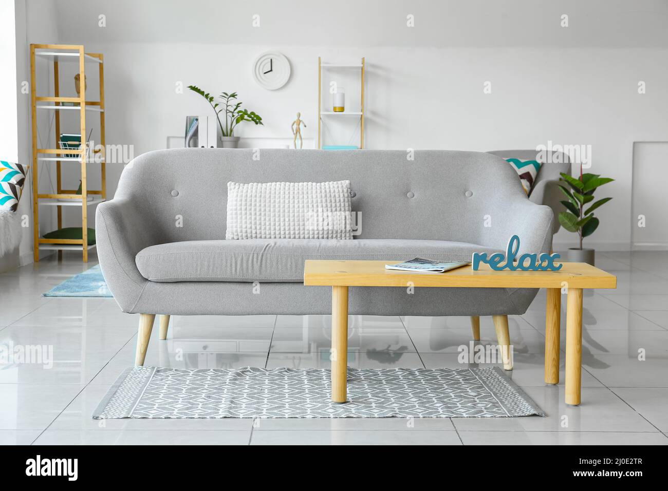 Interior of light living room with grey sofa and table Stock Photo - Alamy
