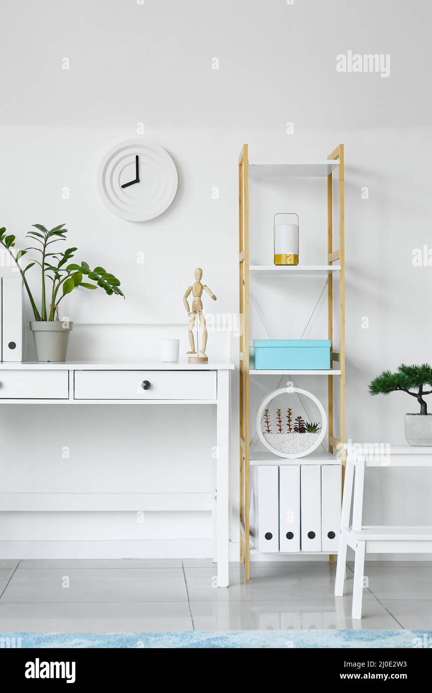 Interior of light living room with clock, table and shelving unit Stock
