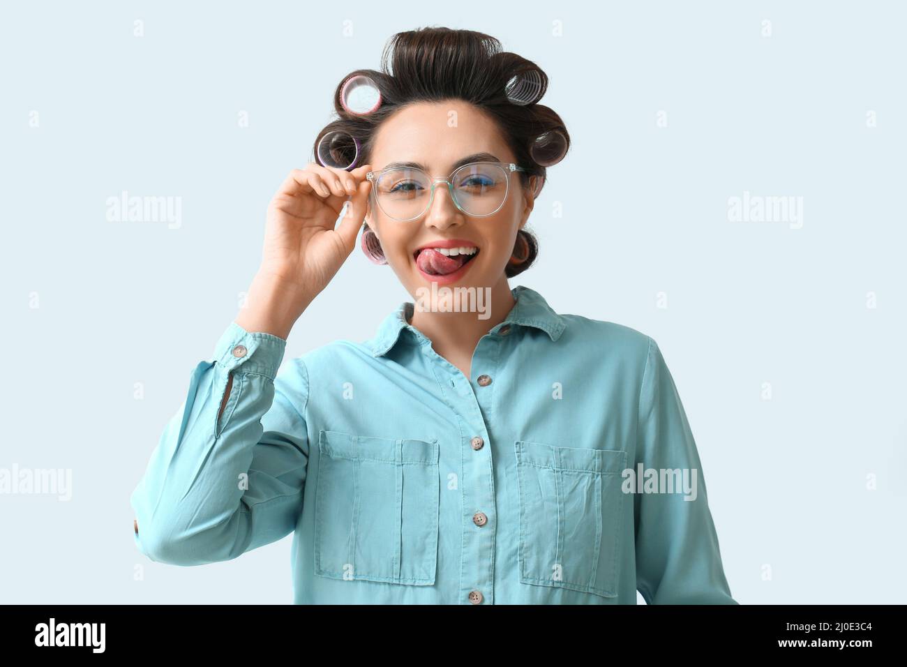Funny young woman in hair rollers on light background Stock Photo Alamy