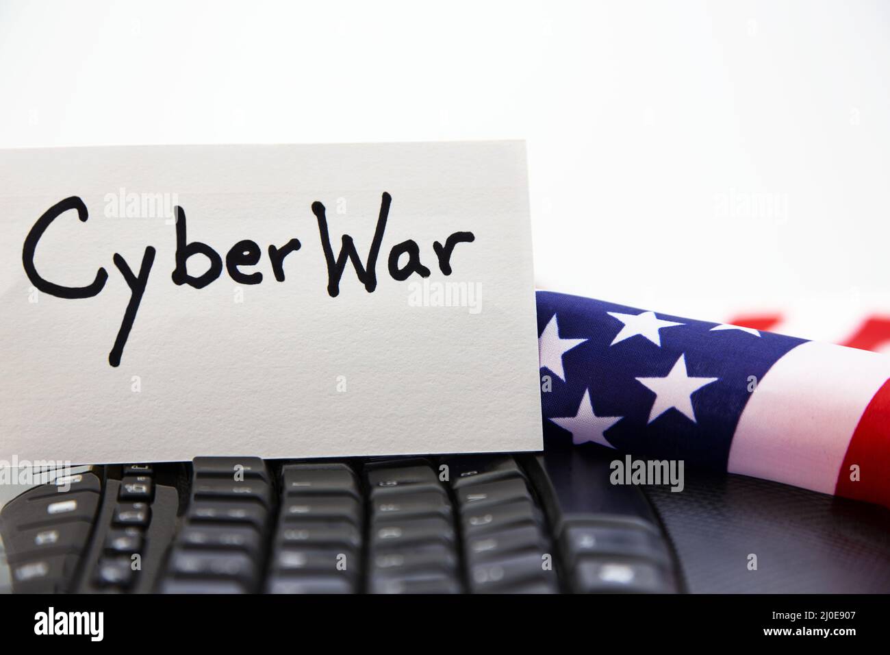 Conceptual image of national threats of cyberattacks against American infrastructure seen in flag, keyboard, and CYBERWAR card still life Stock Photo