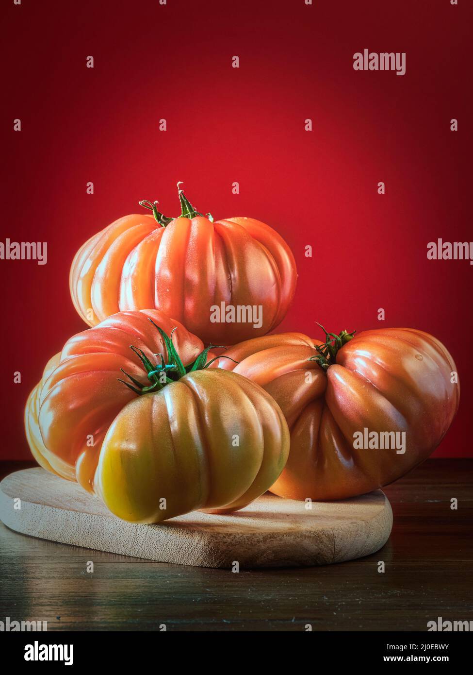 Close-up of three ripe tomatoes placed on a wooden board. Red ...