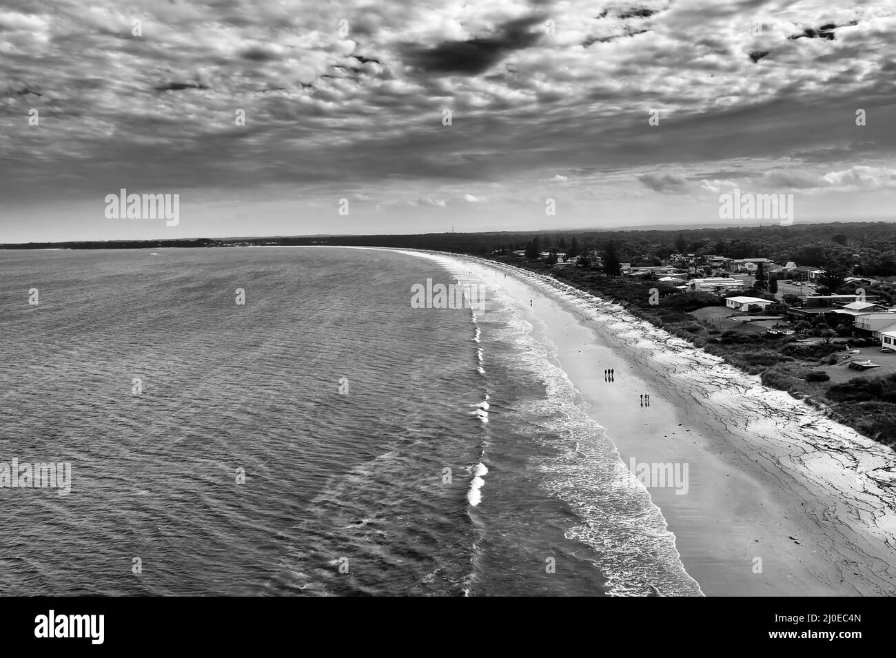 Moody black white view of long stormy Callala beach and town waterfront on Jervis bay of Australian pacific coast. Stock Photo