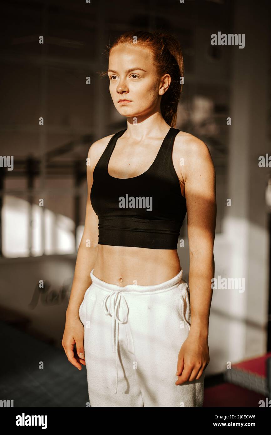 Portrait . Young attractive woman whit serious face look. athlete in sport clothes in the gym . sunset Stock Photo