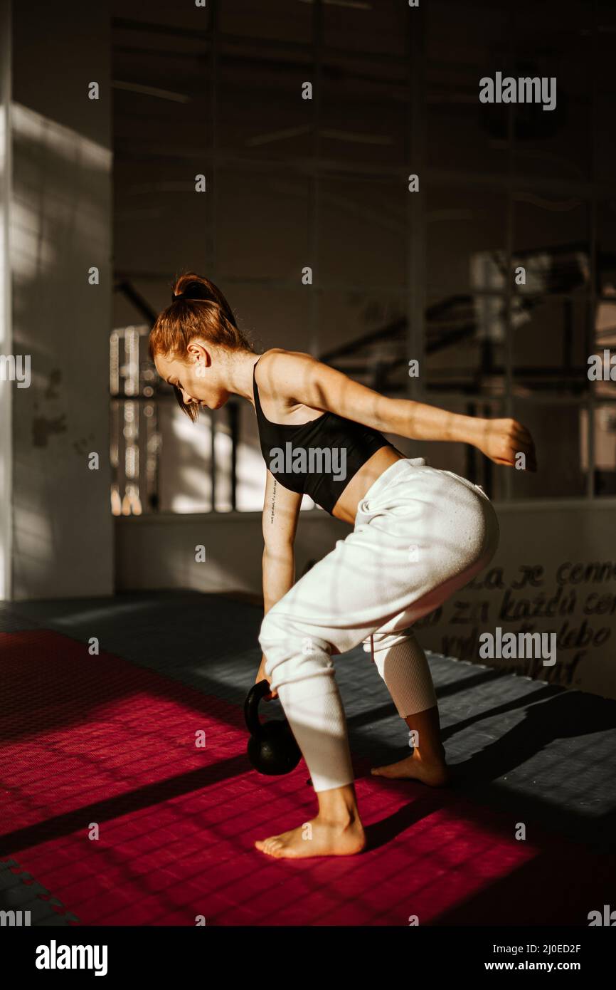 woman doing dumbbell swing. girl in the back who is practicing strength training Stock Photo