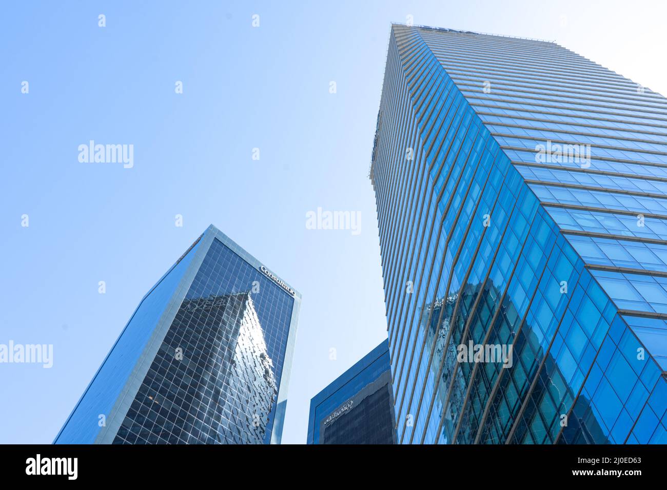 Skyscraper glass facades on a bright sunny day with sun beams in the blue sky. Modern buildings of Buenos Aires. View from below Stock Photo