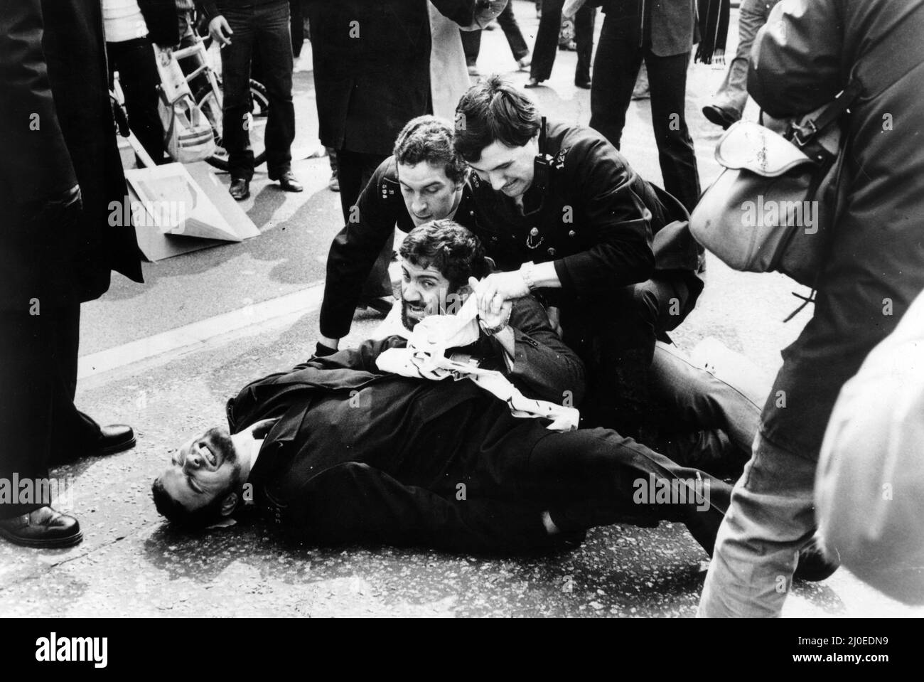 Second day of the Iranian Embassy Siege in London where six gunmen of the Iranian extremist group 'Democratic Revolutionary Movement for the Liberation of Arabistan' stormed the building, taking 26 hostages before the SAS retook the embassy and freed the hostages. Police officer Michael Perkin lies on the ground,  his face contorted in agony after having his leg broken by an angry pro Khomeini demonstrator near the Embassy building.  His colleagues rush to his aid to drag the man off. 1st May 1980. Stock Photo