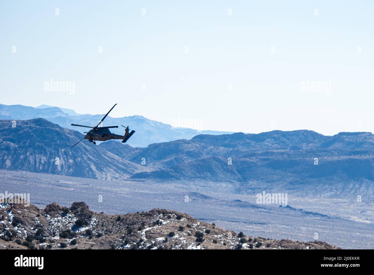 An HH-60 Pave Hawk assigned to the 55th Rescue Squadron searches for a stranded pilot during a combat search and rescue exercise during Red Flag-Nellis 22-2, at the Nevada Test and Training Range, March 10, 2022. The Nevada Test and Training Range is the U.S. Air Force’s Premier military training area with more than 12,000 square miles of airspace and 2.9 million acres of land. (U.S. Air Force photo by Airman Trevor Bell) Stock Photo