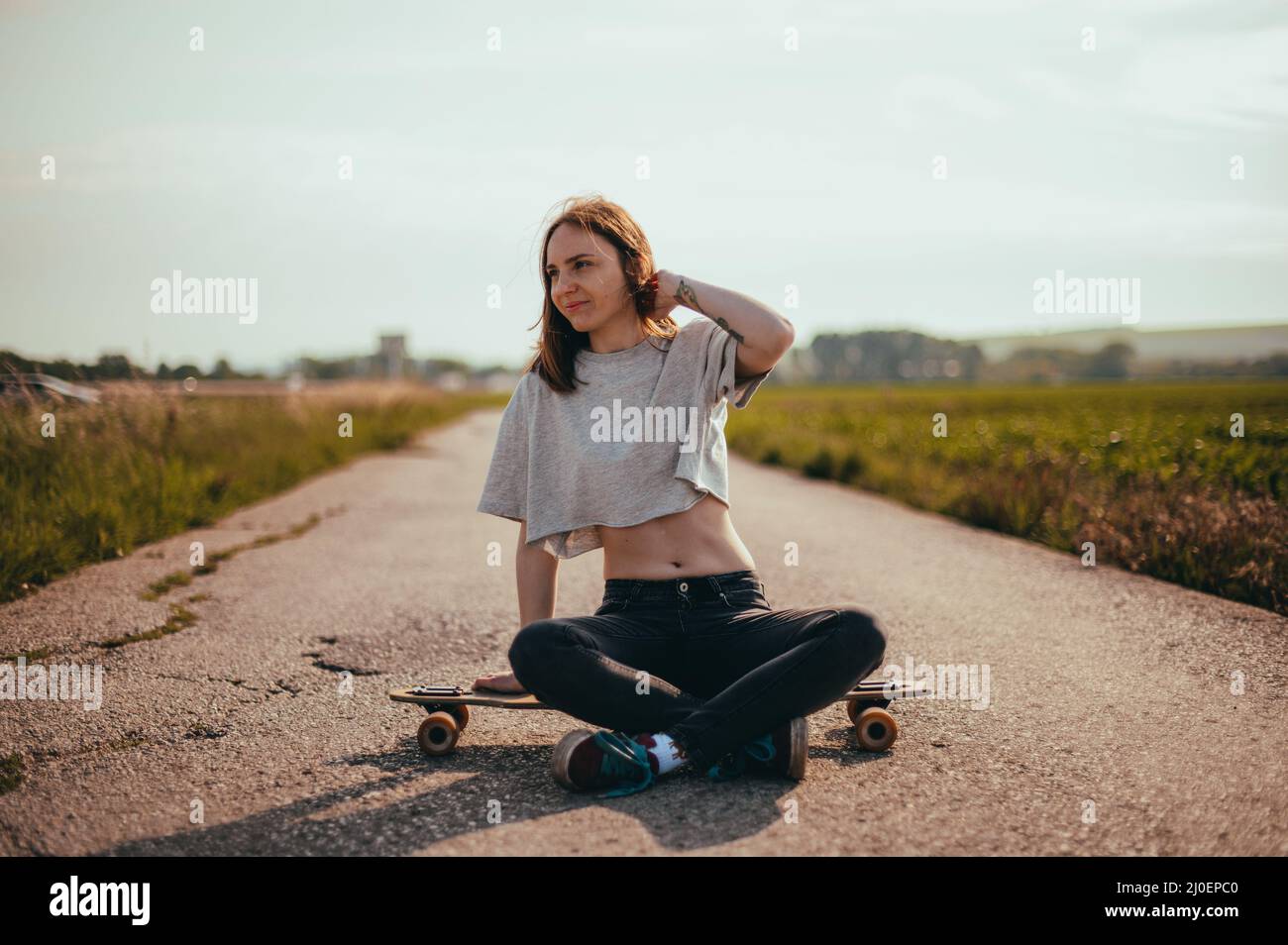 Portrait of a young pretty girl sitting on a longboard. lifestyle photo. woman riding a longboard Stock Photo