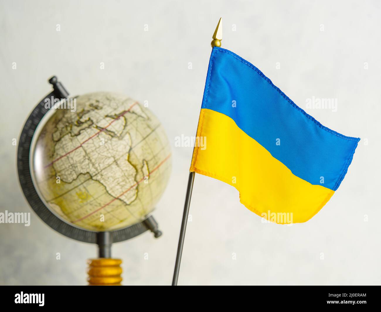 State flag of Ukraine and a globe on a white background. The war in Ukraine, the Russian invasion, the killing of civilians and children, the destruct Stock Photo