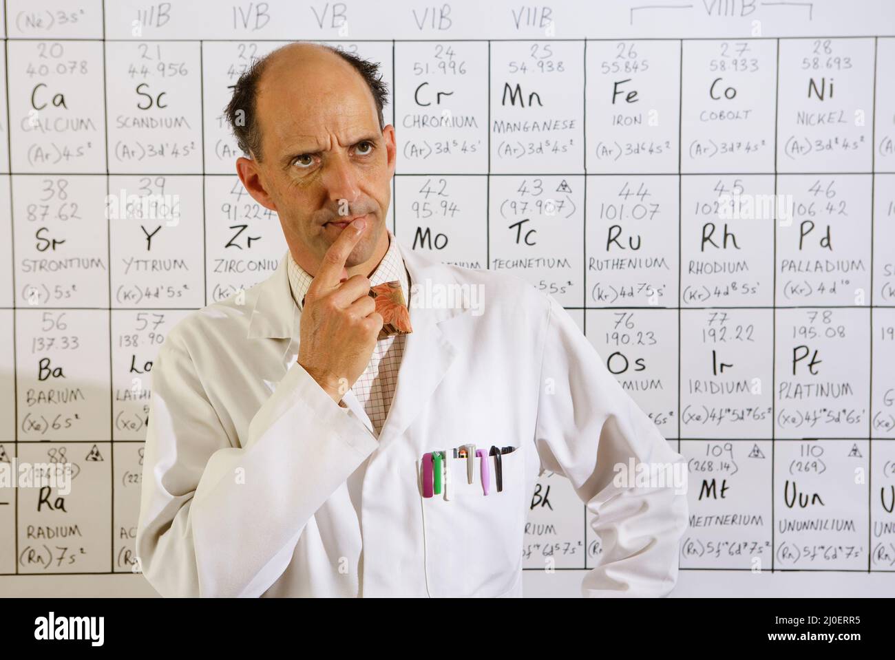 Middle aged caucasian professor thinking  in front a periodic table Stock Photo