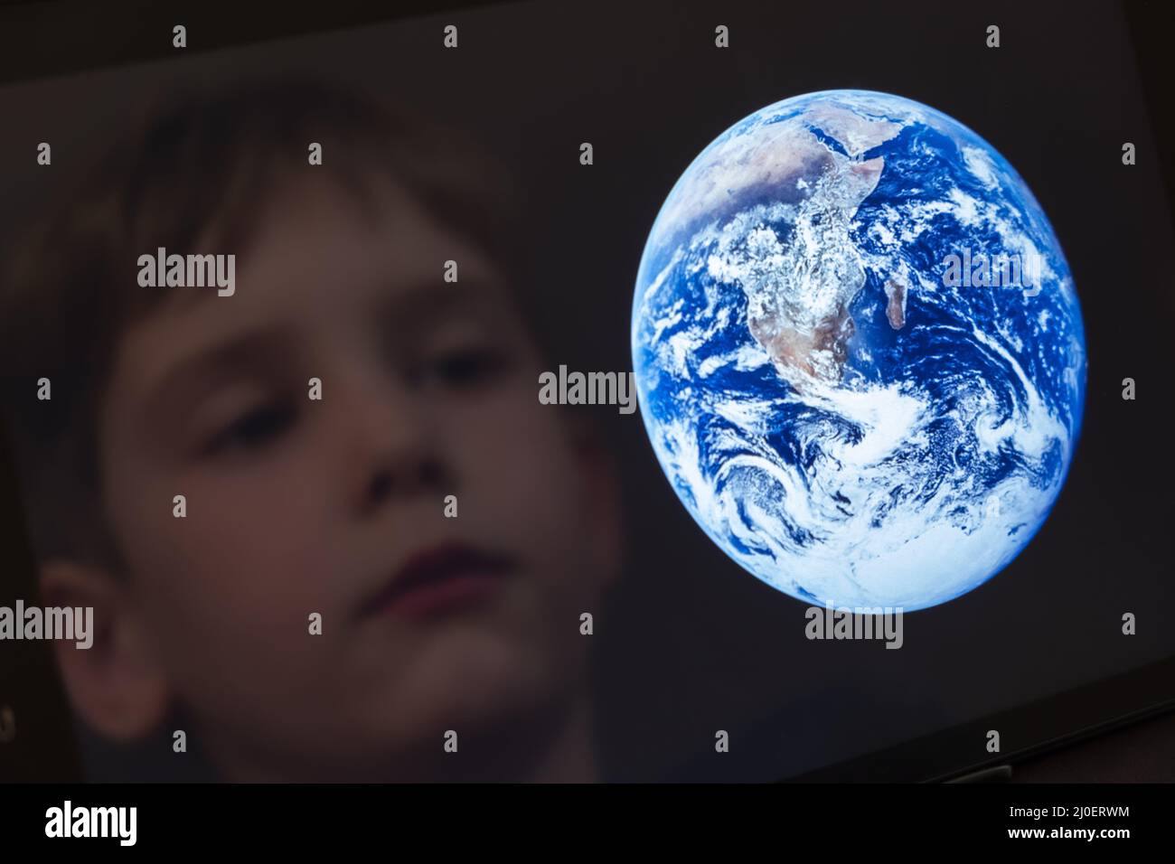 Reflection of a young boy looking at the earth on a tablet computer Stock Photo