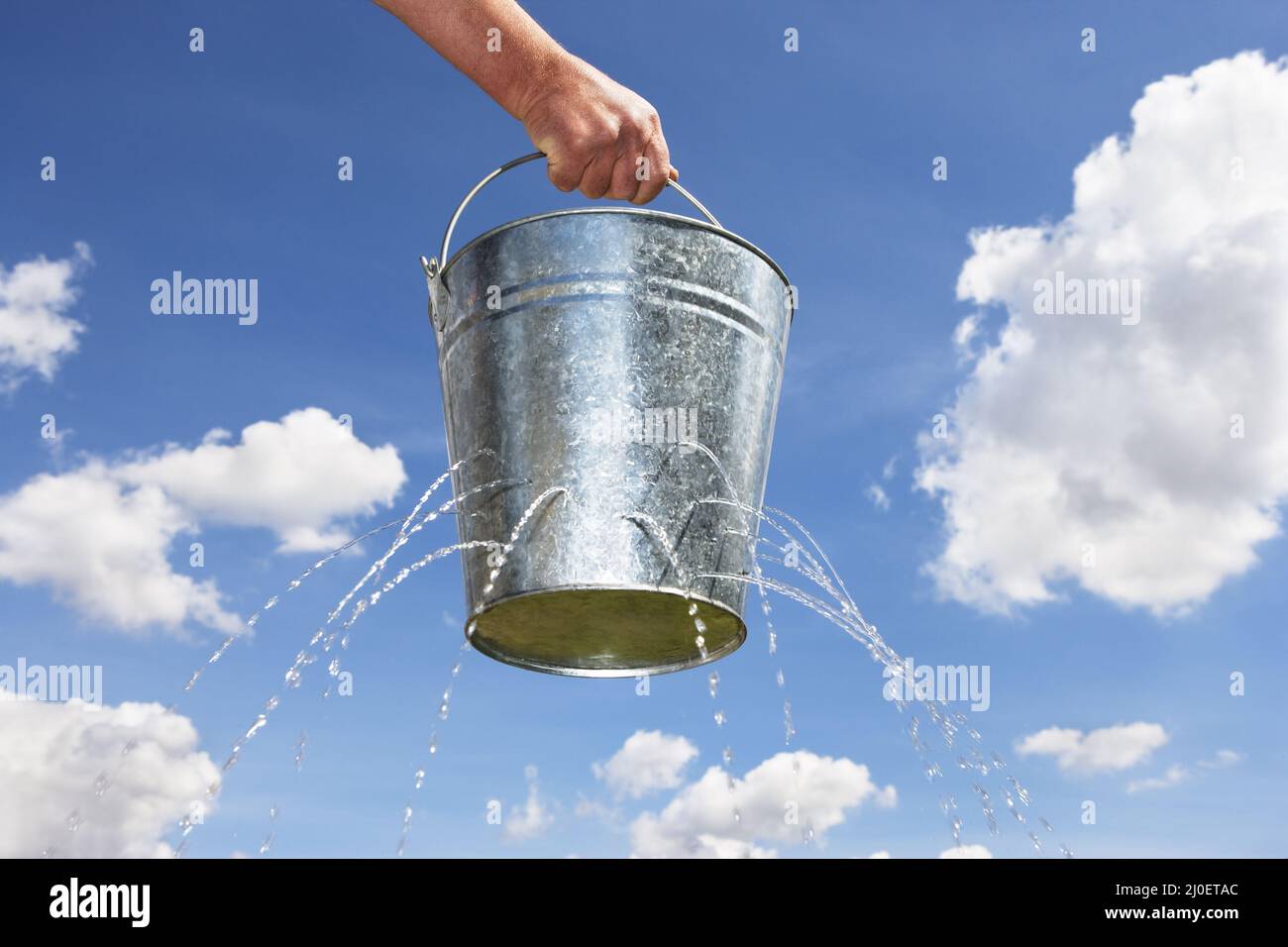 Man holding bucket with holes leaking water Stock Photo