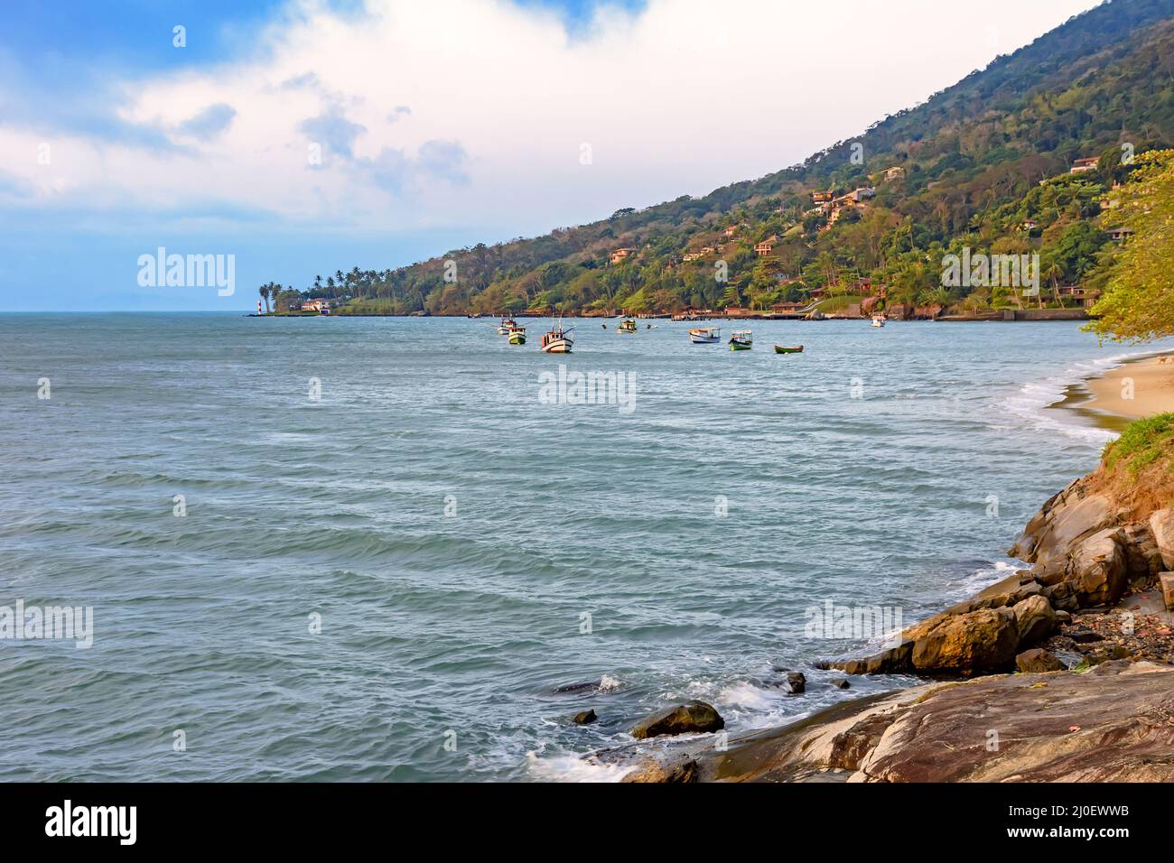 Beach with tropical vegetation and boats over the sea in Ilhabela island Stock Photo