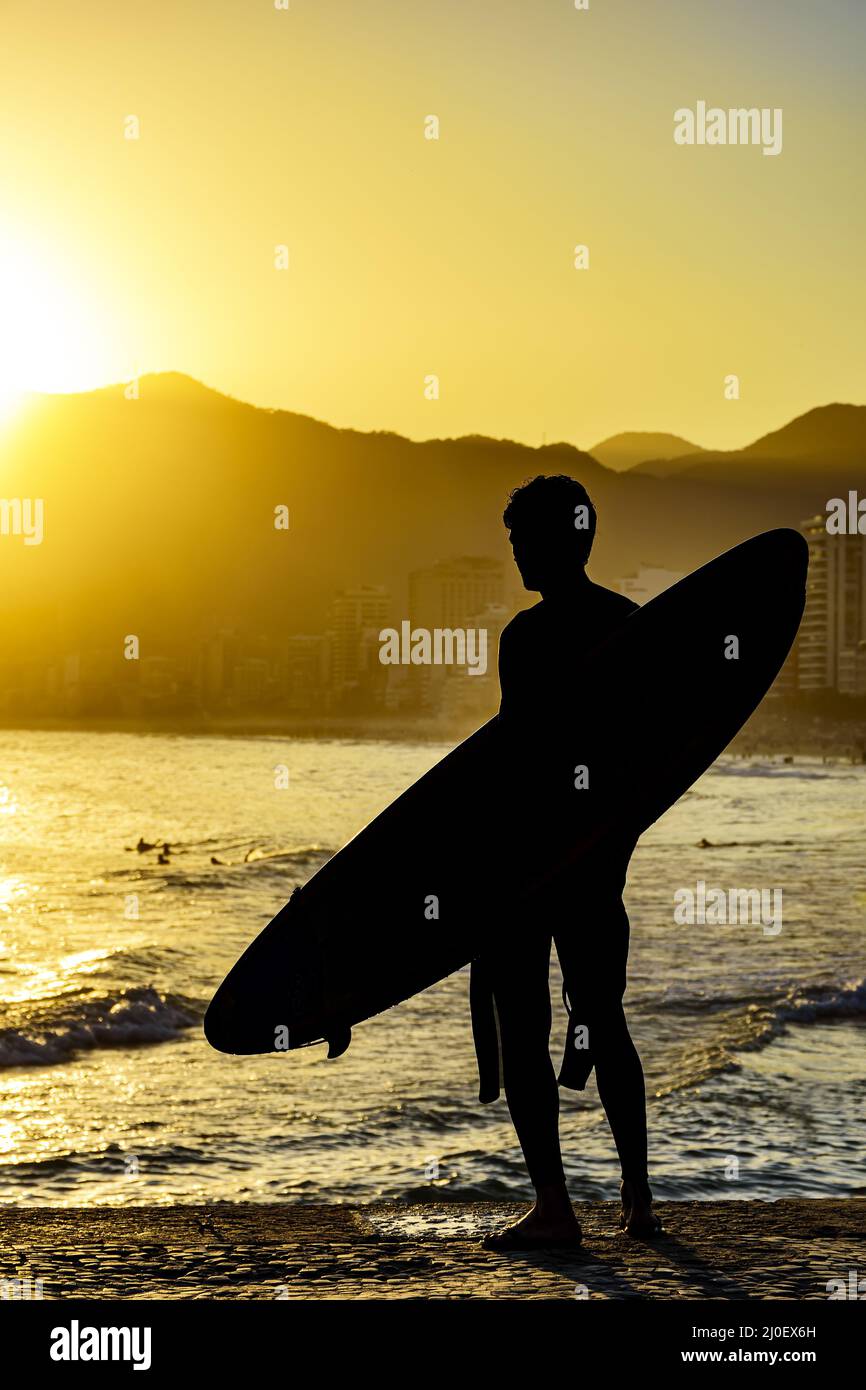 Surfer silhouette with his longboard looking at the Iapnema beach Stock Photo