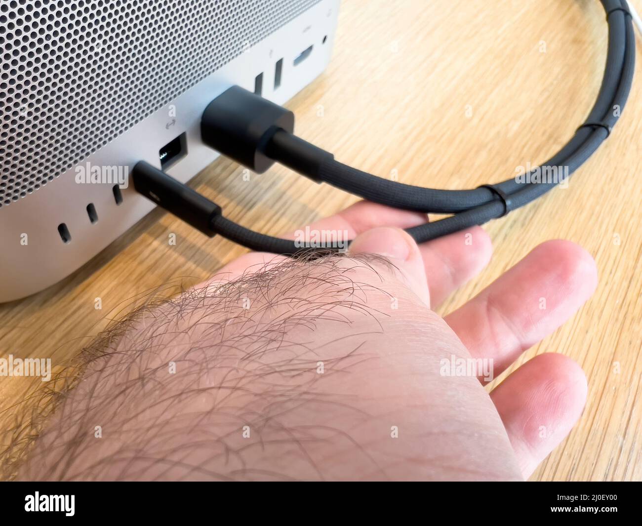 Paris, France - Mar 18, 2022: POV male hand holding braided cable of new Apple Computers Mac Studio M1 Ultra with connection - thunderbolt, 10gbe, usb-a, hdmi ports Stock Photo