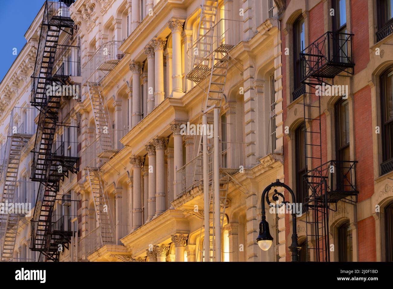 Facades of Soho loft buildings with fire escapes at dusk. Lower Manhattan, New York City Stock Photo