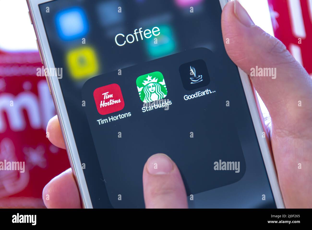 Calgary, Alberta. Canada Dec 28 2019. A person holding an iPhone looking coffee apps from Tim Hortons, Starbucks and Good Earth. Stock Photo