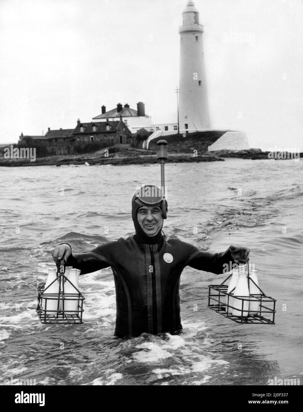 A picture from a series of humurous novelty images taken by Sunday People photographer Dennis Hutchinson.   A milkman in a wetsuit tries to deliver milk to St Mary's Island, Whitley Bay ay high tide.    Circa: 1980 Stock Photo