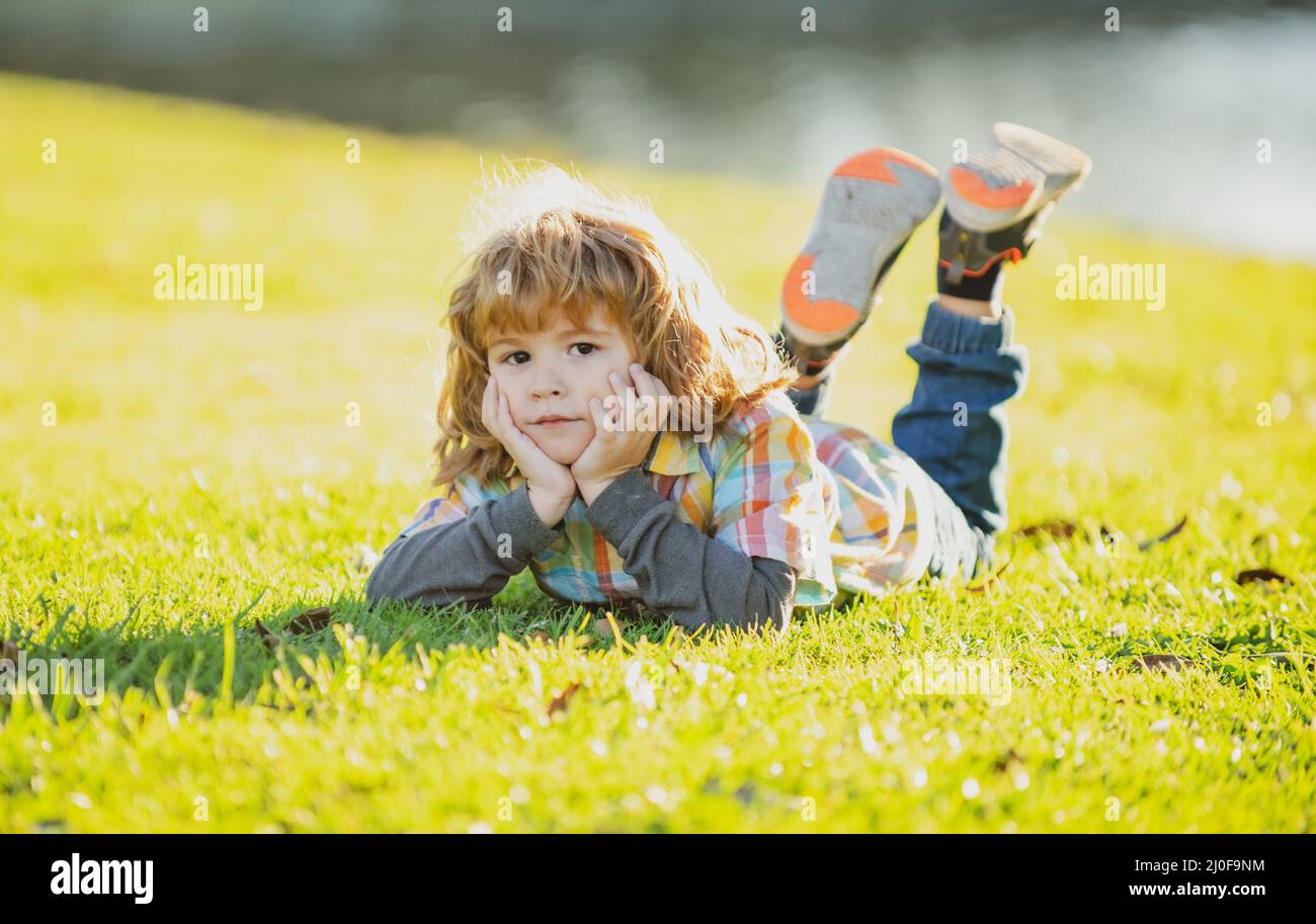 Child outdoor. Kid in park. Spring Boy lying on grass. Summer walk