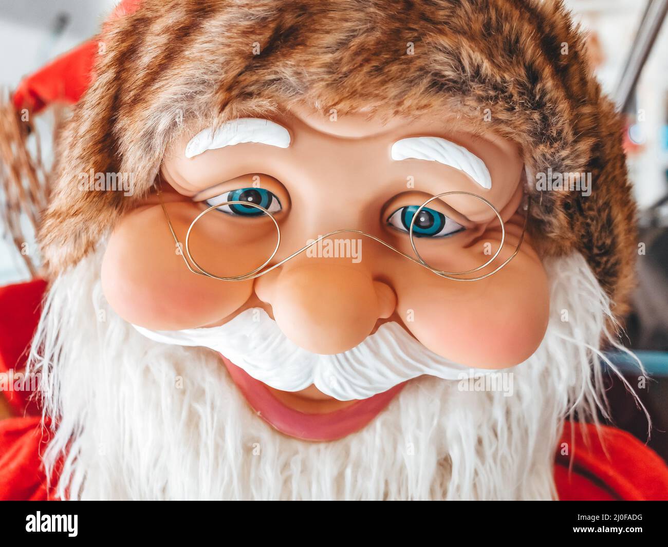 Toy smiling face of rubber santa claus with blue eyes and wire glasses. Stock Photo