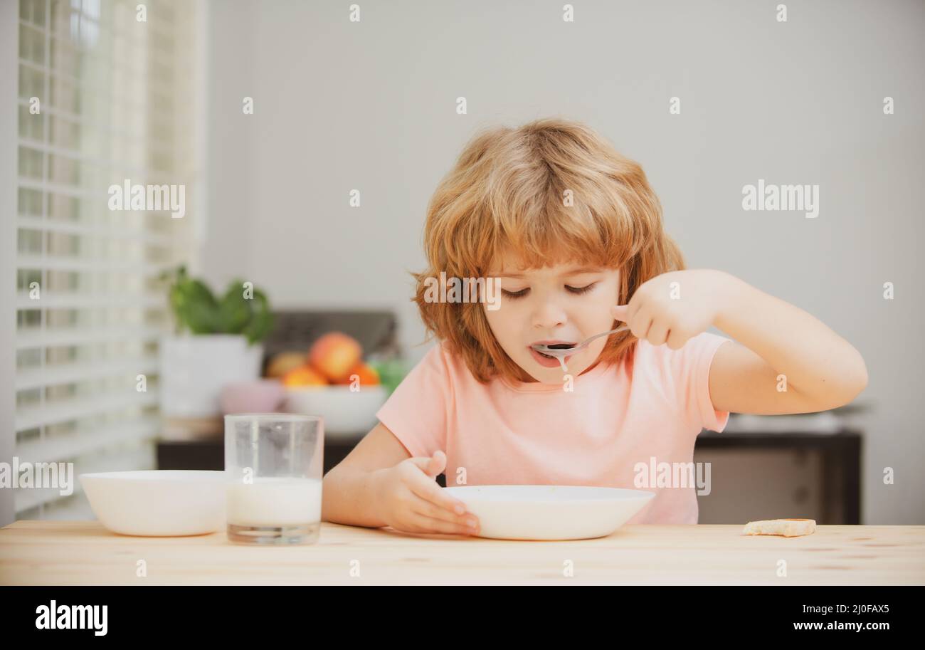 Little healthy hungry baby boy eating soup from with spoon. Child nutrition. Stock Photo
