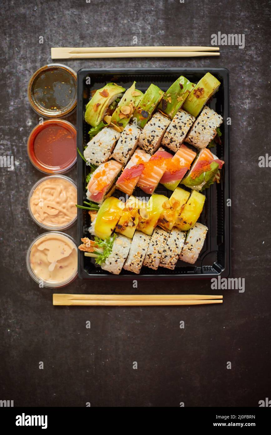 Asian food delivery home, various sushi sets in plastic containers with