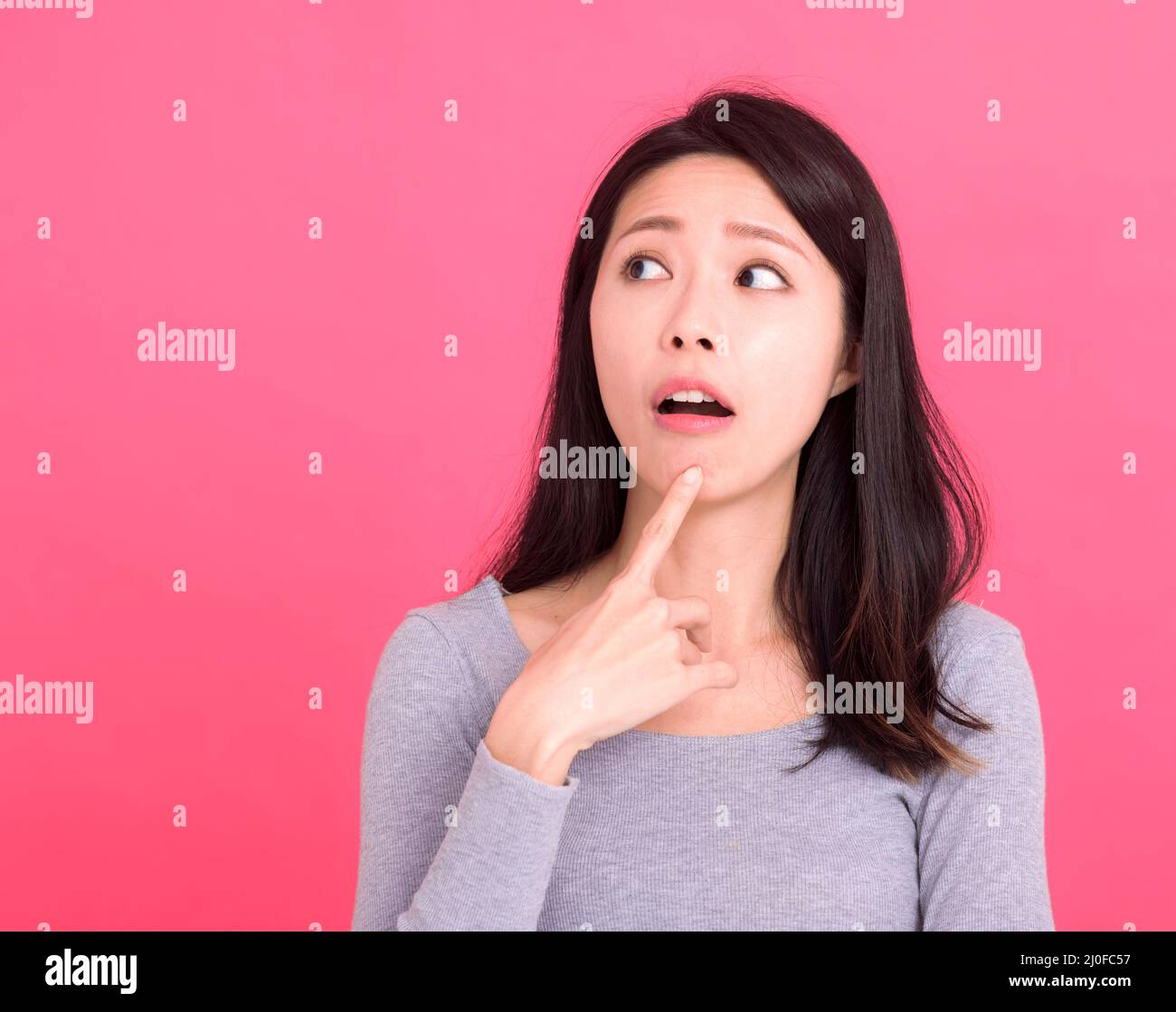 young woman serious look empty space think ponder minded deep idea isolated on pink background Stock Photo