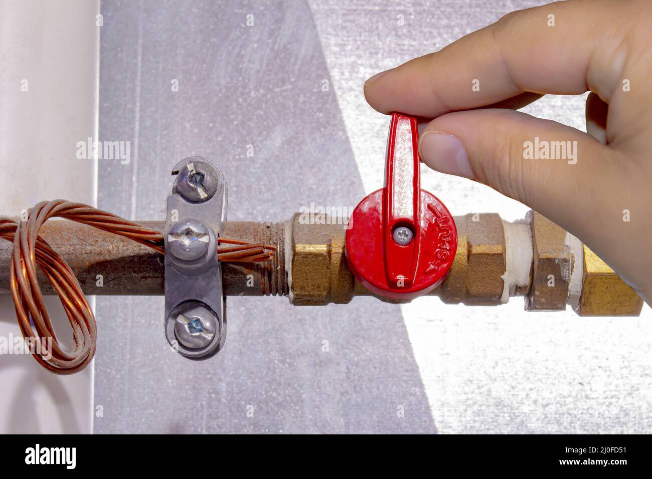 A person turning on off a natural gas red tap Stock Photo Alamy