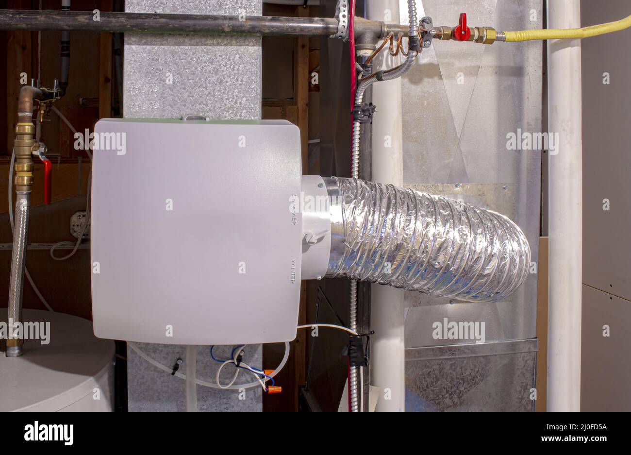 A home humidifier attached to the return duct with a bypass connection to the supply hot air duct. Stock Photo