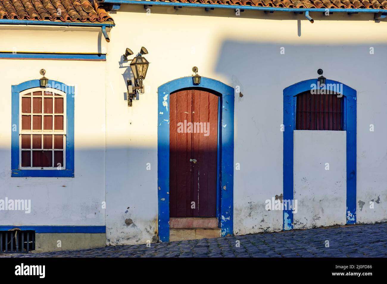 Facade of old house in colonial architecture with blue windows and door ...