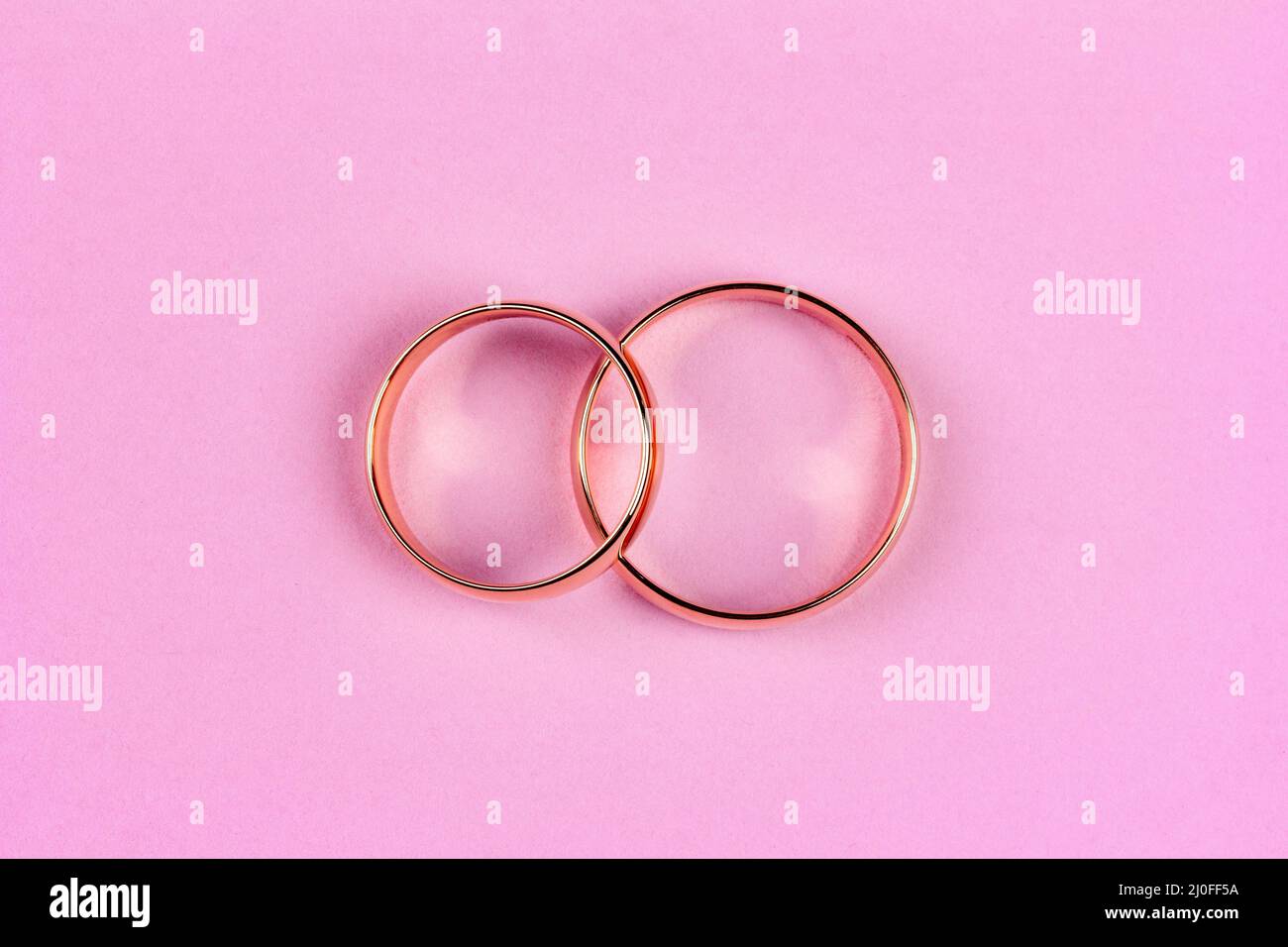 A pair of gold wedding rings on a pink background, top view flat lay Stock Photo