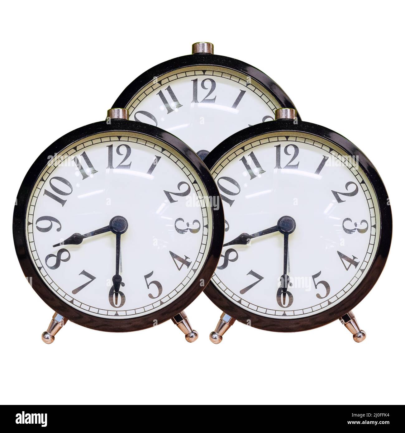 Three identical alarm clocks with white dial and black numbers on an isolated background Stock Photo