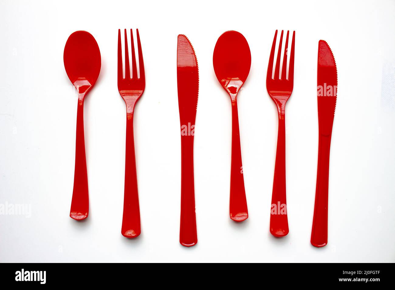Single use red plastic cutlery on a white background. Concept: Ban single use plastic Stock Photo